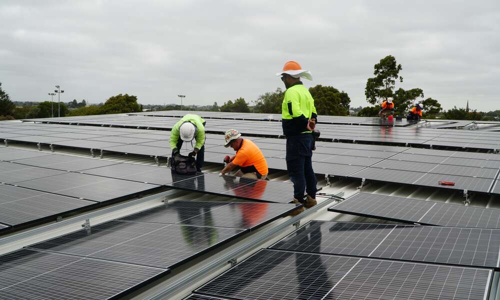 Crews installing solar panels on the roof of the Wulanda Recreation and Convention Centre.