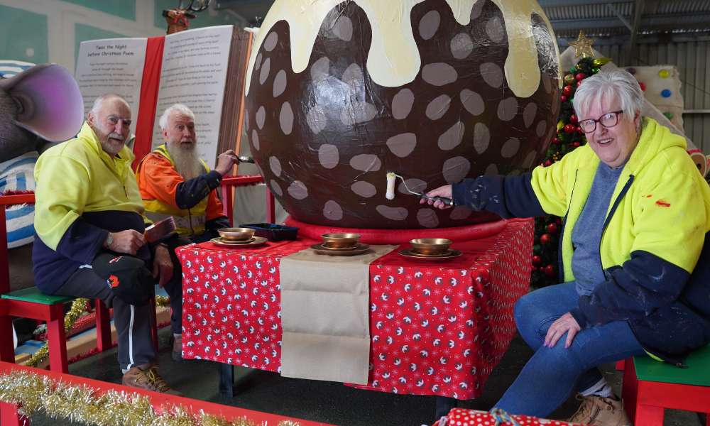 Christmas Parade volunteers Alan Liptrott and Tom and Helen Telford put some finishing touches on The Christmas Pudding float.