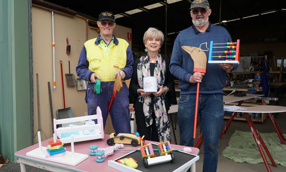 Men's Shed members Ian Bond and Peter Heness presented City of Mount Gambier Mayor Lynette Martin with 100 handcrafted wooden toys for distribution as part of the Mount Gambier Community Mayor's Christmas Appeal.