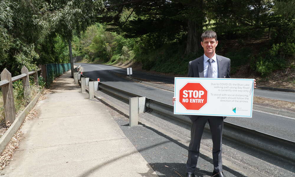 City of Mount Gambier General Manager City Infrastructure Nick Serle with signage to alert pedestrians to follow the one-way, clockwise only directive along the Bay Road section of the Blue Lake walking path.